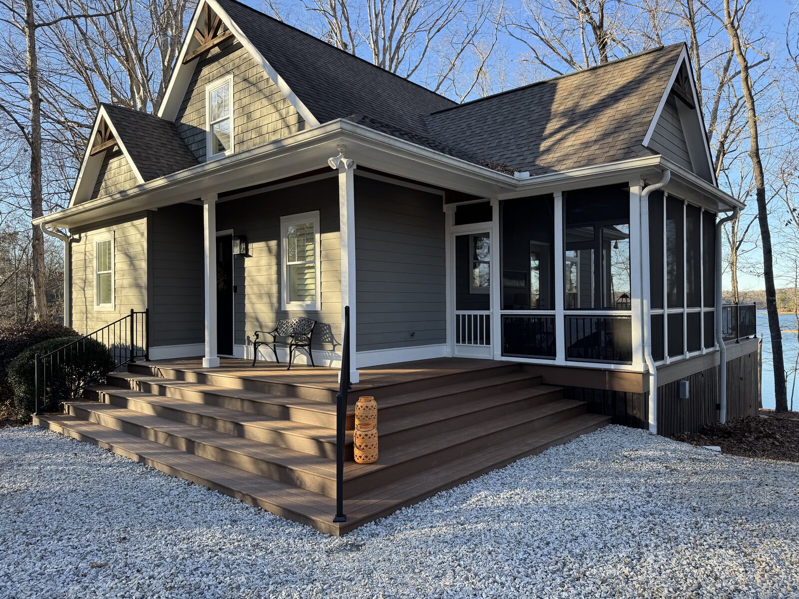 An after-image of a completed and newly-stained exterior corner staircase with sleek black metal railings at the corner of the L-shape and on the open side.