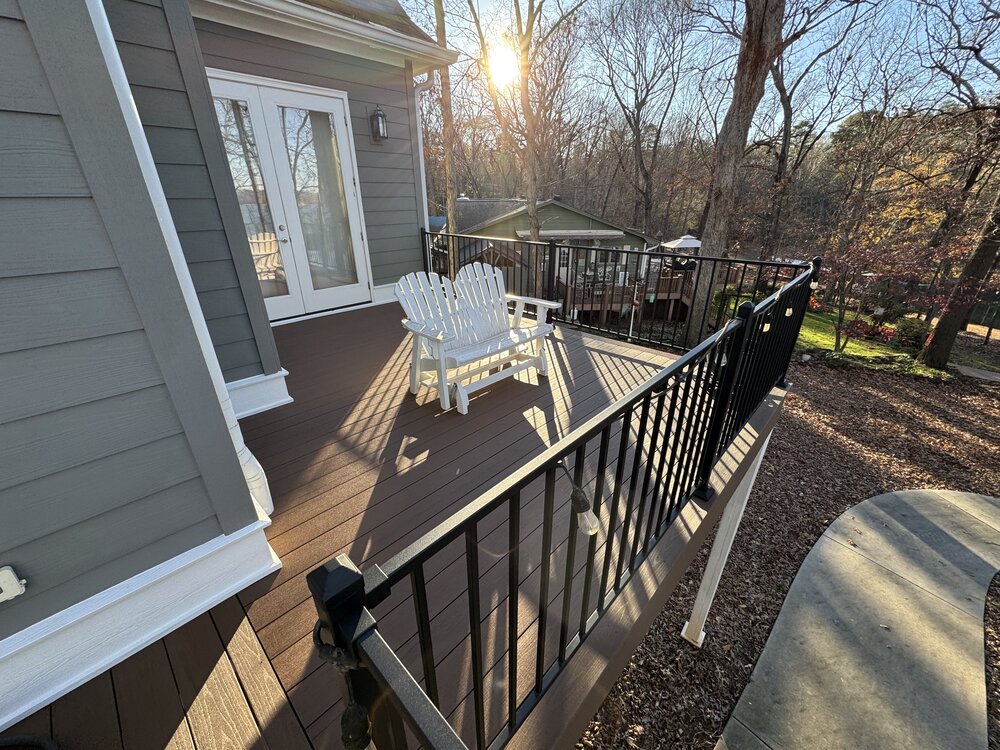 another corner of the deck with white Adirondack bench sitting in the sun, with the new black railings all around