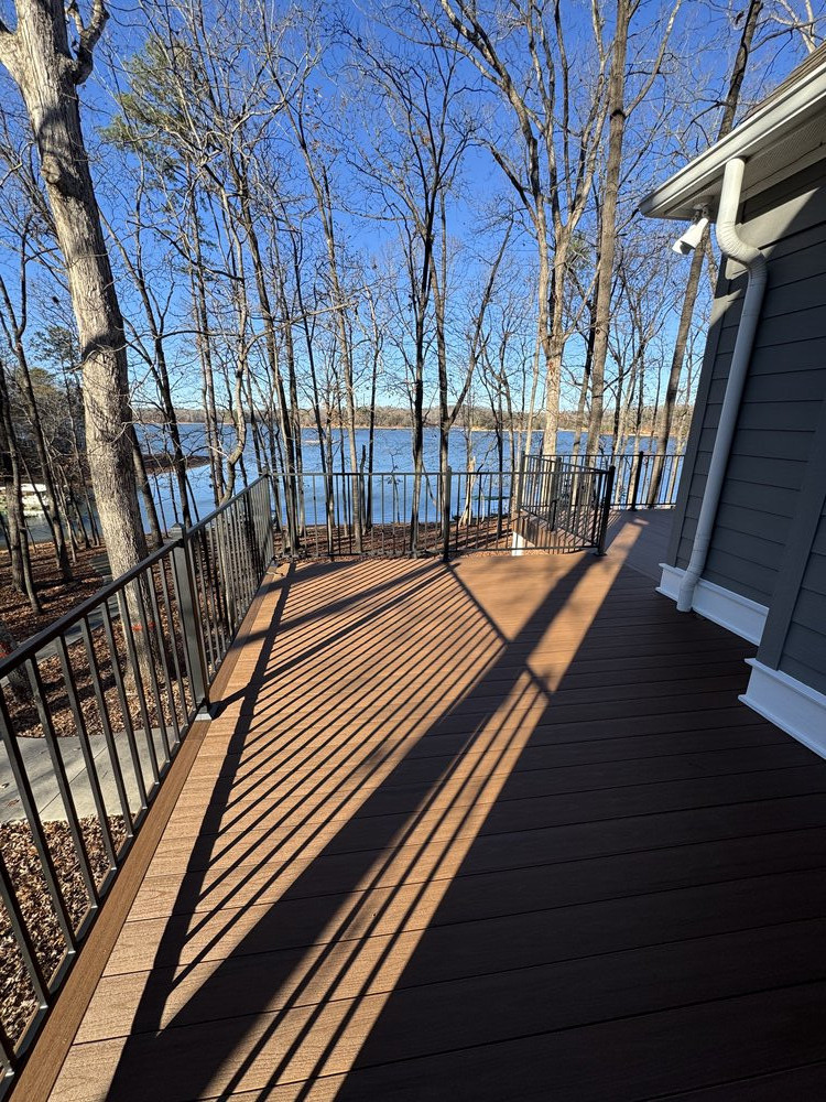 after image of same view of house with newly built deck and sleek black metal railing installed, replacing the prio white wood trimmed rails