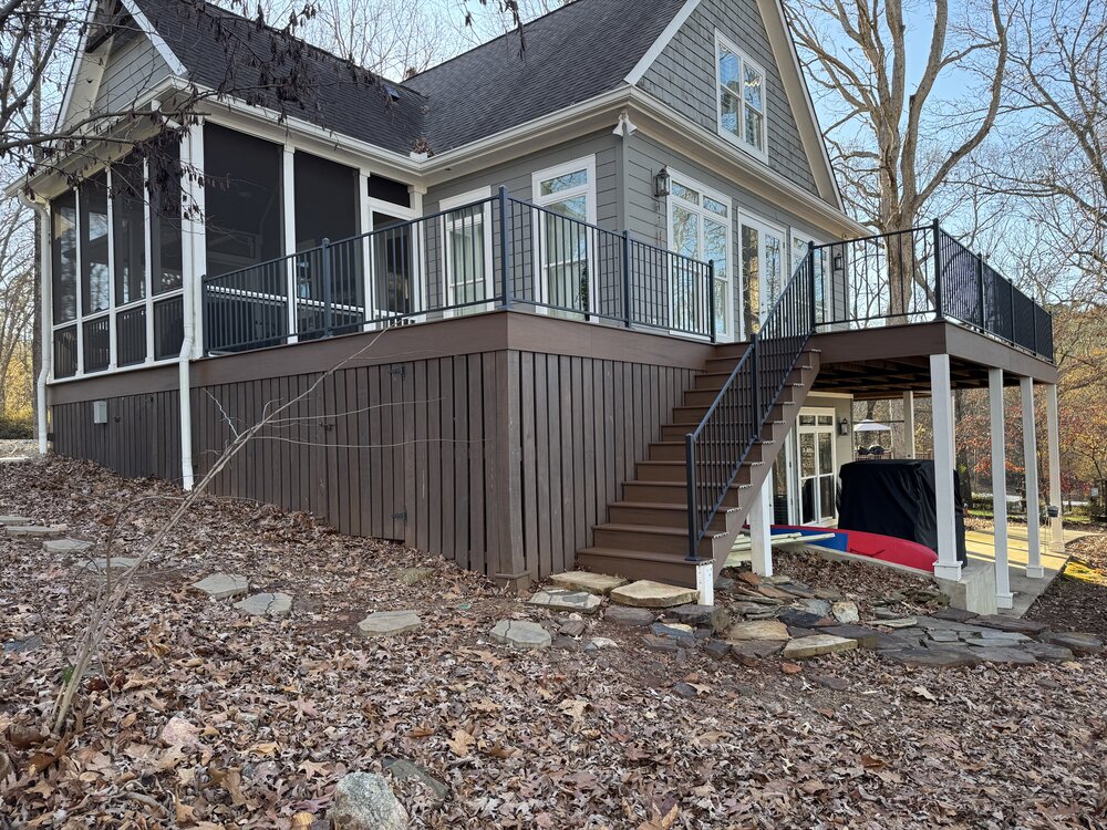 side of house with newly built wood deck and sleek black metal railings all around, allowing beautiful view of lake front
