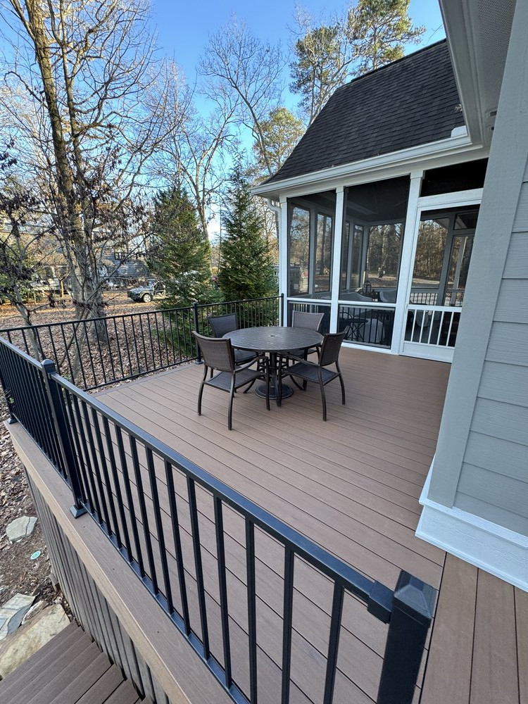 black metal patio table and four chairs sit on corner of house on newly built deck