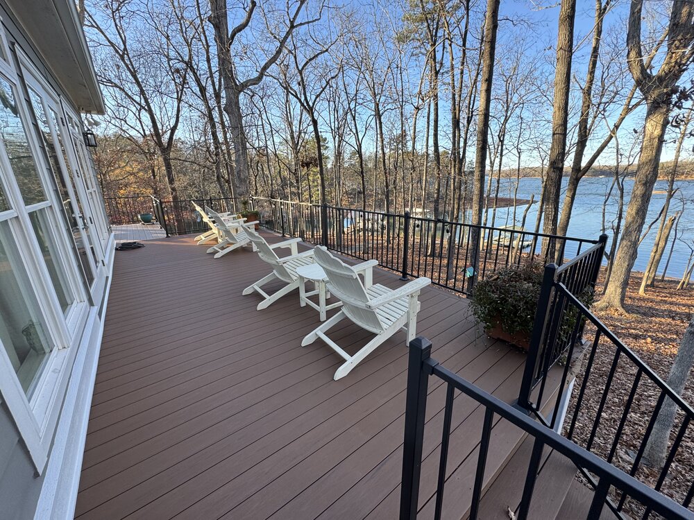 large newly built top deck has new sleek black metal railing all around the deck, and 4 white Adiorndack chairs sit on deck to enjoy the lake views