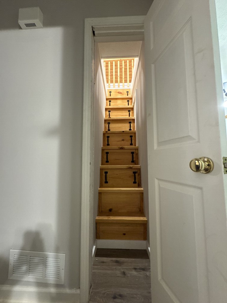 remodel is complete and showing stairway built with 9 treads that leads up to the loft above. The stairway treads have black metal handles revealing built-in storage inside each stair.