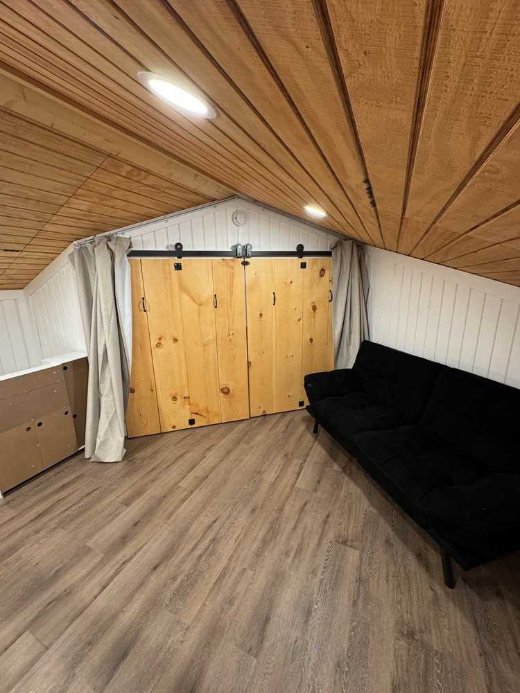 completed loft remodel with beautiful laminate flooring, and showing custom barn-style bi-fold doors made for the large opening above the lower floor