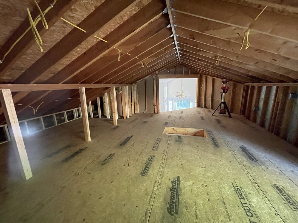 remodel progresses with new plywood sheets laid on top of insulation, creating the sub floor. A rectangle hole has been cut into floor for the new stairwell access. A large hydrolic jack is holding up the roof corner until beams are replaced