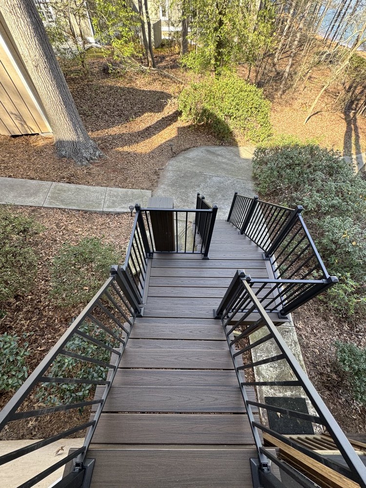 black metal patio table and four chairs sit on corner of house on newly built deck
