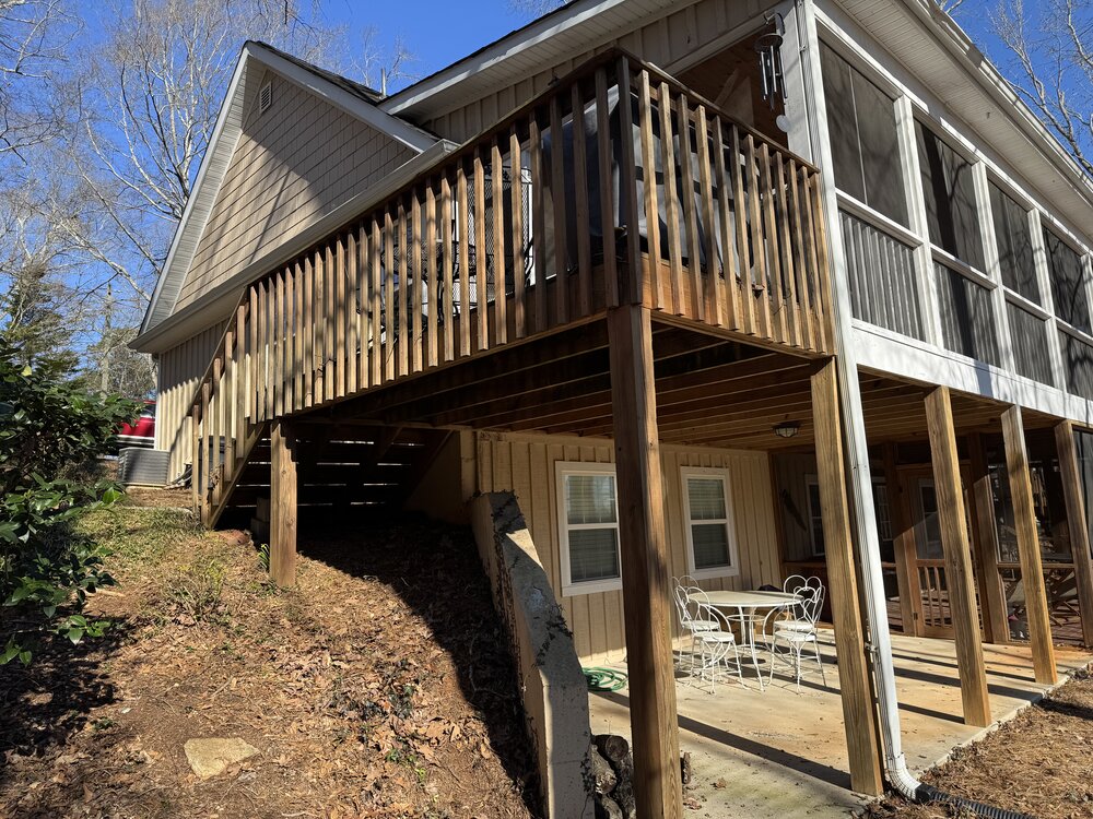 view of side porch before work from the back side of lake house, showing old wooden rails, posts, and stairs