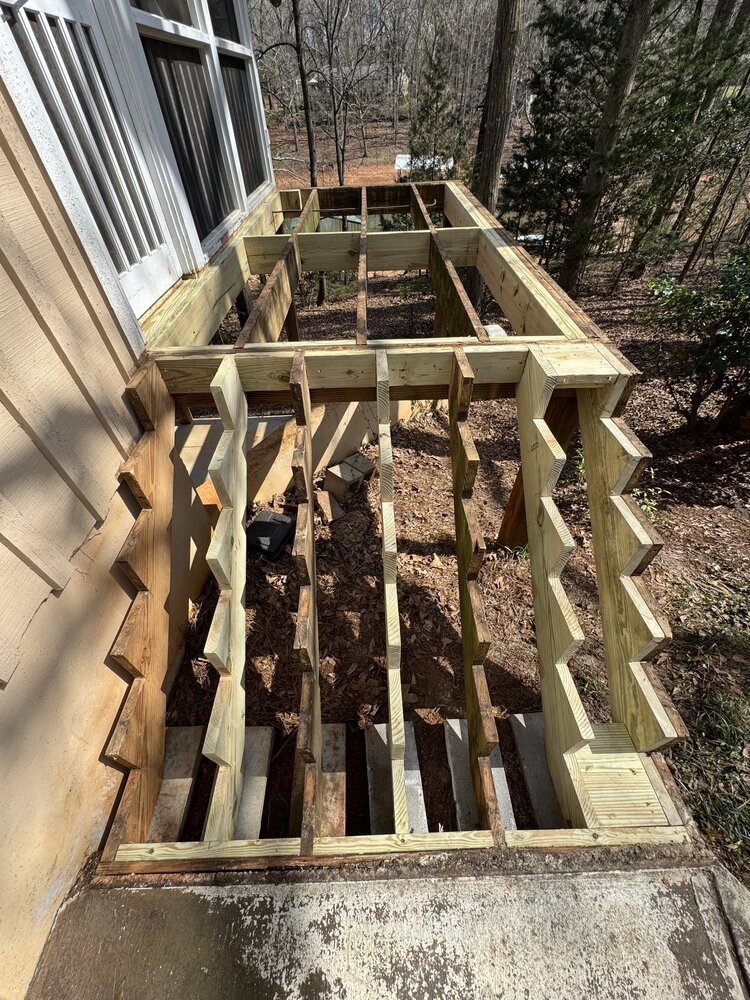 demo accomplished on side wood porch and wood stairs, displaying new wood stair stringers and new porch studs in place