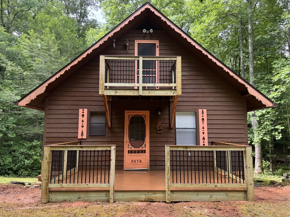 Beautiful shot of a mountain cabin with a newly built Trex deck with aluminum picket railings and elegant design.