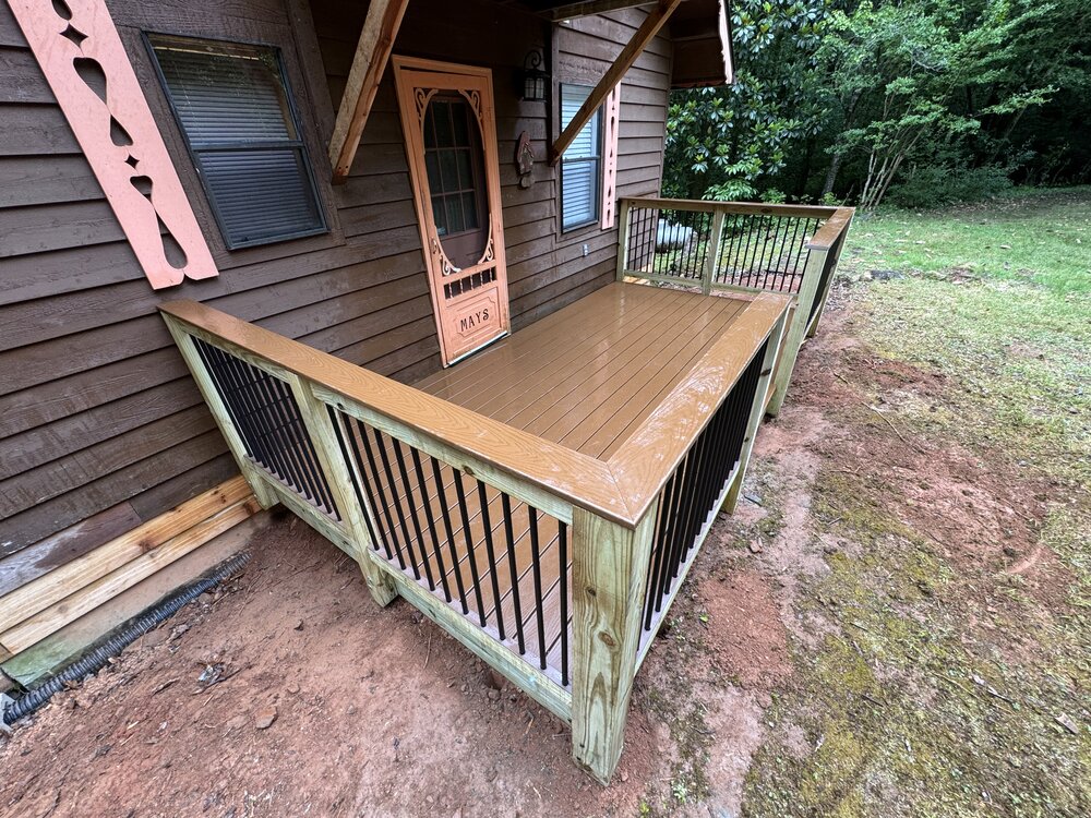 Opposite angle of the finished deck of the cabin, showing a close up of the finished cabin Trex deck and aluminum picket railings.